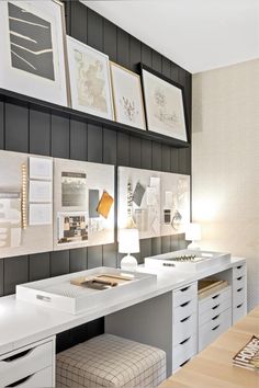 a white desk topped with lots of drawers under framed pictures on the wall above it