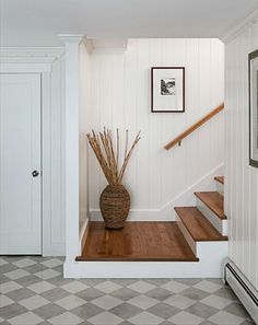 a vase sitting on top of a wooden floor next to a stair case in a house