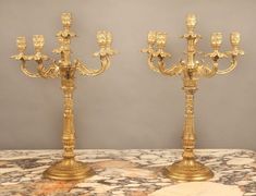 two golden candelabras sitting on top of a marble table