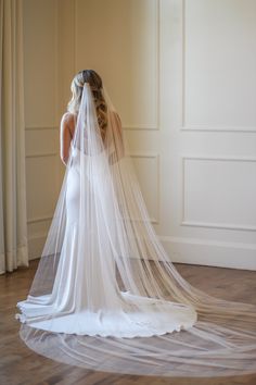 a woman in a wedding dress with a veil on her head is looking down at the floor