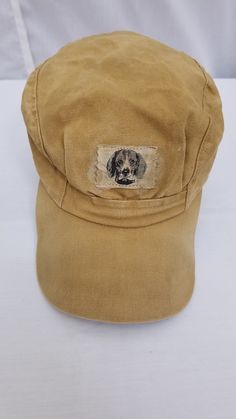 "Vintage Dark Tan Mohawk Hunting Hat Baseball Cap with Ear Flaps and Dog Logo.  Worn in vintage condition.  The owner's name is written on one of the ear flaps.  Cap can be worn with the ear flaps down or tucked into the cap.  6 7/8\" measurement." Baseball Vintage, Hunting Hat, Dog Logo, Hat Baseball, Dark Tan, Trucker Cap, Baseball Cap, Caps Hats, Accessories Hats