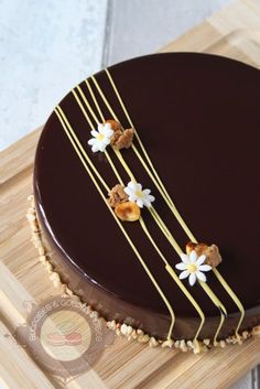 a chocolate cake with white flowers and gold pins on it's side sitting on a cutting board