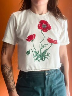 This poppy crop top was inspired by the wildflowers of Texas in Spring. Our designs are original illustrations and each shirt is printed by hand in our garage on 100 percent cotton, super soft, Bella + Canvas shirts. Crop tops have a raw edge at the bottom. Because our shirts are printed using environmentally friendly, water-based inks, our prints are soft to the touch and (like all other screen-printed shirts) will start to look slightly weathered with time. For the longevity of your shirt, please wash it inside-out on a cold setting.  Dry on low or air-dry. Due to the handmade quality of our shirts, each one is slightly different.  Your shirt is one-of-a-kind and made with love! Vintage Hand-printed Relaxed Fit Top, Vintage Hand Printed Crew Neck Tops, Vintage Hand Printed Cotton Top, Spring Graphic Print Cropped Shirt, Spring Cotton Graphic Cropped Shirt, Spring Graphic Tee Cropped Cotton Shirt, Spring Cropped Shirt With Graphic Print, Spring Crew Neck Crop Top With Screen Print, Spring Floral Embroidery Cotton Crop Top