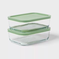 two glass containers with green lids are stacked on top of each other