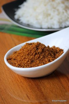 a white bowl filled with rice next to a spoon on top of a wooden table