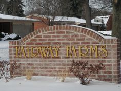 a brick sign that says tahway farms in front of snow covered bushes and trees