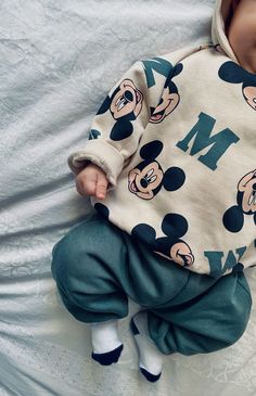 a baby laying on top of a bed wearing a mickey mouse outfit