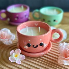 a pink cup sitting on top of a wooden table next to two small cups filled with candles