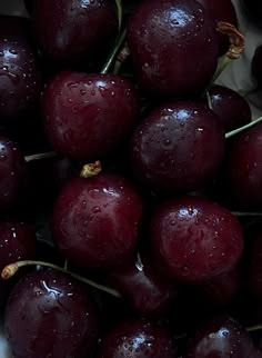 a bunch of cherries sitting on top of each other with water droplets all over them