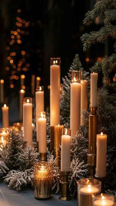 candles are lined up on the table with evergreen branches