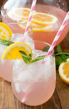 two glasses filled with lemonade and garnish on top of a wooden table