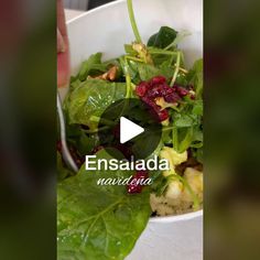 a salad with spinach and cranberries in a white bowl on top of a table