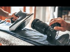 a person holding a camera and taking pictures on a bed with an ironing board