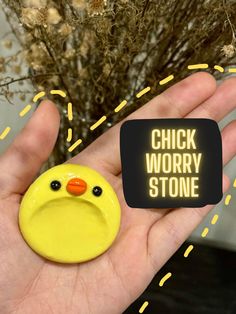 a hand holding a yellow rubber ducky with the words chick worry stone on it