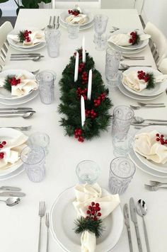 the table is set for christmas dinner with white plates and silverware