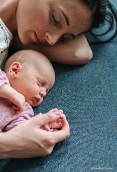 a woman laying on the floor holding a baby