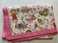 two pink and white quilts on top of each other, one with an image of children's toys