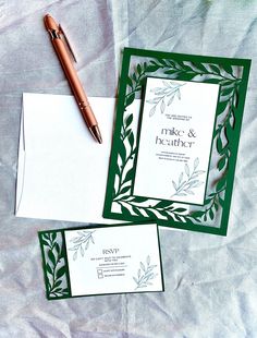 two green and white wedding stationery with a pen