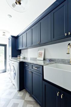 a kitchen with blue cabinets and white counter tops, gold pulls on the faucet