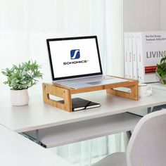 an open laptop computer sitting on top of a wooden desk next to a potted plant