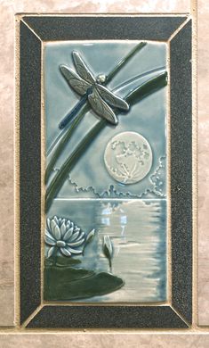 a dragonfly sitting on top of a tile wall next to a lily pad with water lilies