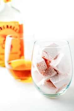 a glass filled with marshmallows next to a bottle