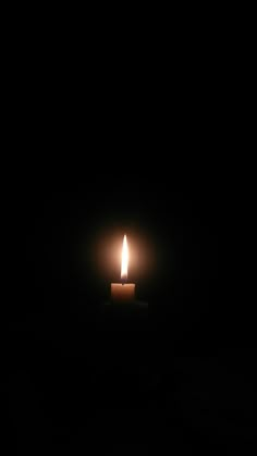 a lit candle in the dark on a black background