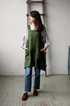 a woman standing in front of a ladder with her hands on her hips and looking off to the side