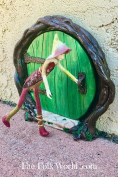 a figurine is standing in front of a green door with a pink flower on it