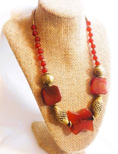 Tribal is composed of wonderfully large carnelian focal beads, especially the uniquely shaped center bead. It is accented with open woven brass Baule beads from Africa as well as the large round brass beads and Kenyan brass heishi beads. Bohemian Red Agate Beads, Bohemian Gold Beads With Natural Stones, Large Bronze Bohemian Beads, Bohemian Large Bronze Beads, Bohemian Carnelian Beads For Jewelry Making, Bohemian Brass Beads For Gifts, Bohemian Brass Beads As Gift, Gold Carnelian Beaded Necklaces In Bohemian Style, Bohemian Brass Jewelry With Polished Beads