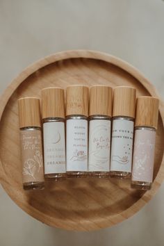 four small jars with labels on them sitting in a wooden bowl