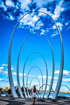 a woman is standing in front of an art sculpture that looks like three spirals