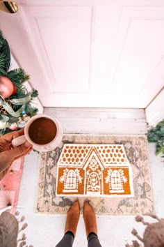 two people are standing in front of a door with a gingerbread house rug on the floor