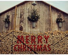 christmas decorations are displayed on logs in front of a barn