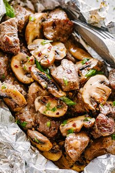 meat and mushrooms in foil with a fork