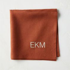 an orange linen napkin with the letters e k m on it