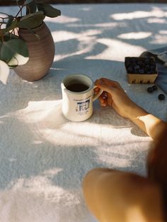 a woman is sitting at a table with a cup of coffee