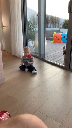 a toddler sitting on the floor in front of sliding glass doors