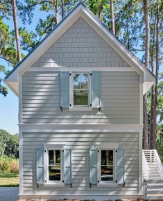 a white house with shutters on the front and stairs leading up to it's second story