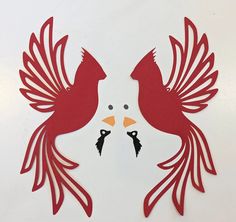 two red birds are facing each other on a white surface