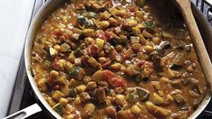 a pan filled with food sitting on top of a stove next to a wooden spoon