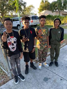 four young men standing next to each other in front of a fence