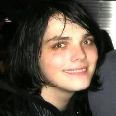 a young man with black hair is smiling at the camera while wearing a leather jacket