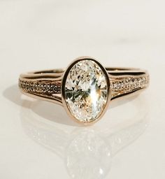 a close up of a ring on a white surface with a diamond in the center