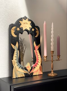 a black dresser topped with a mirror and candles next to a candle holder on top of it