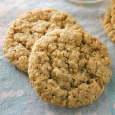 three oatmeal cookies sitting on top of a blue and white table cloth