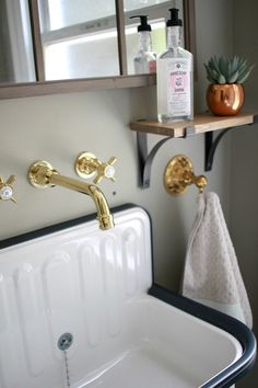 a white sink sitting under a bathroom mirror next to a shelf with bottles on it