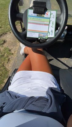 a person is sitting in a golf cart with their feet on the steering wheel and there is a checklist