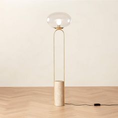 a floor lamp with a round glass shade on it and a black cord connected to the base