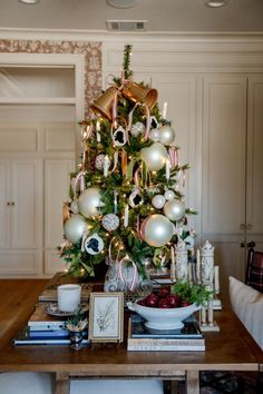 a christmas tree with ornaments on it and other decorations around the base is sitting on a table